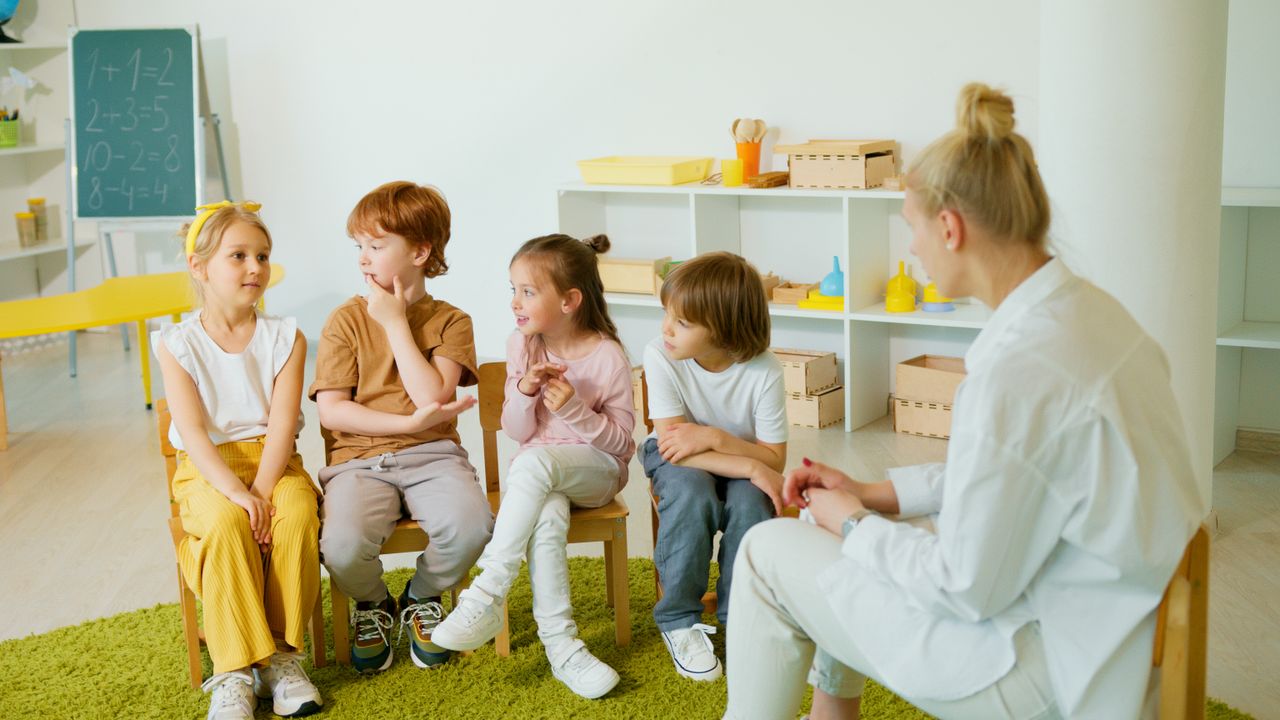 Services A group of children interacting in a classroom with their teacher, fostering learning and social skills.